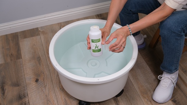 woman adding hydroponic nutrients for her hydroponic tower