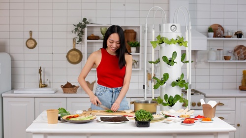Woman harvesting lettuce and herbs from a hydroponic tower garden